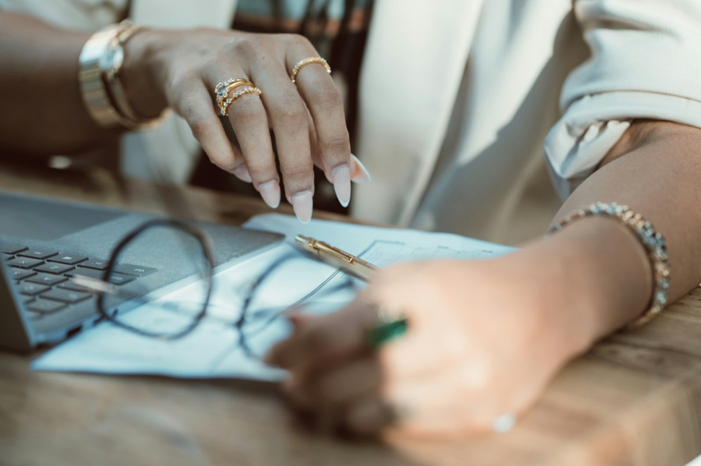 A designer&rsquo;s hands over a sheet of drawings with a pair of glasses