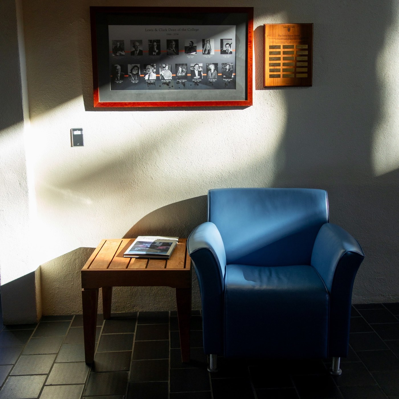 A blue armchair in a sunlit corner beside a small wooden side table
