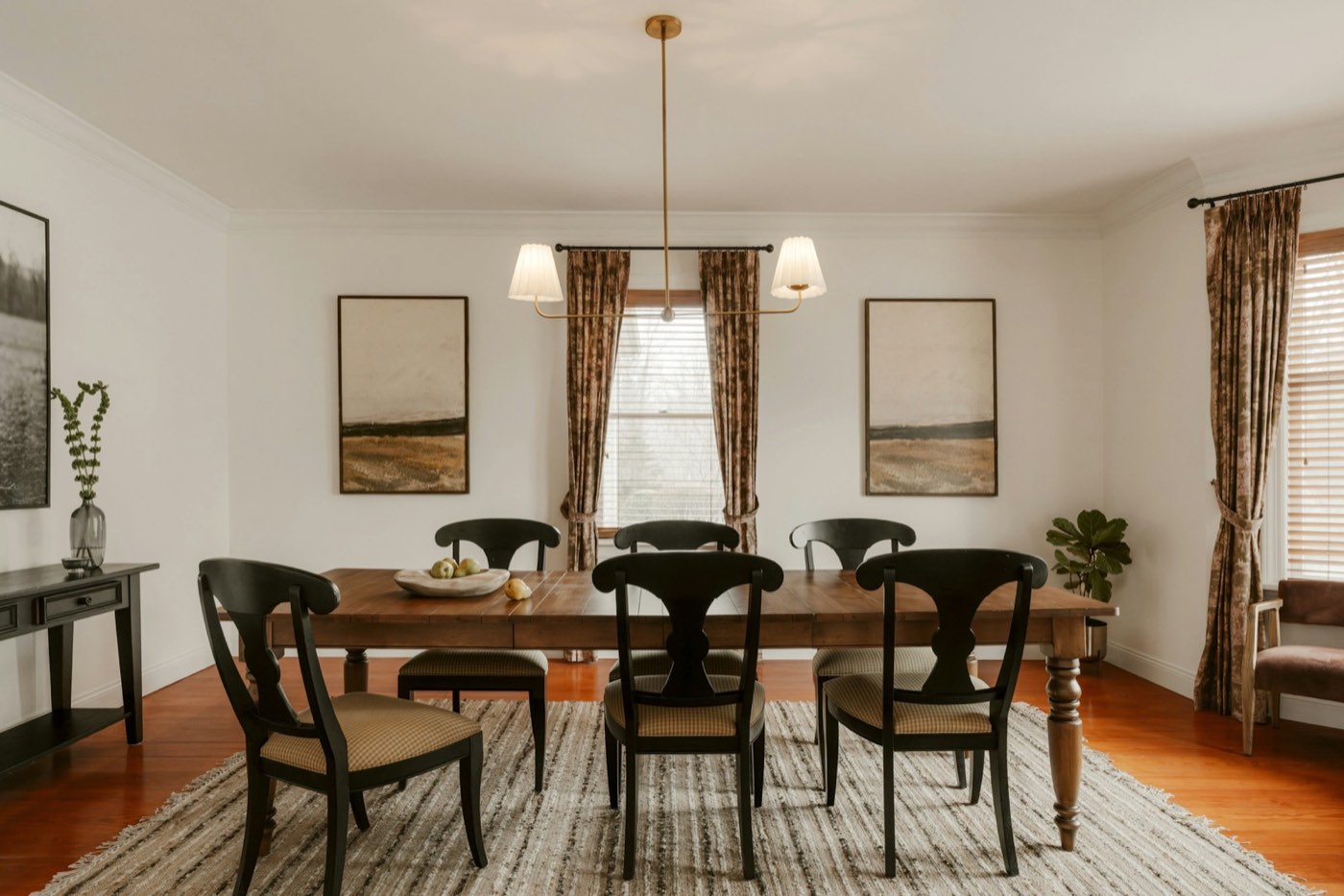 A formal dining room with a long dark table, upholstered chairs and a chandelier